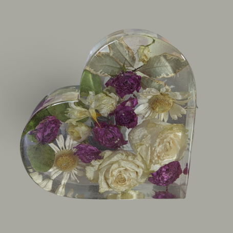 A large resin heart containing dried flowers from a wedding bouquet. Set against a light background.