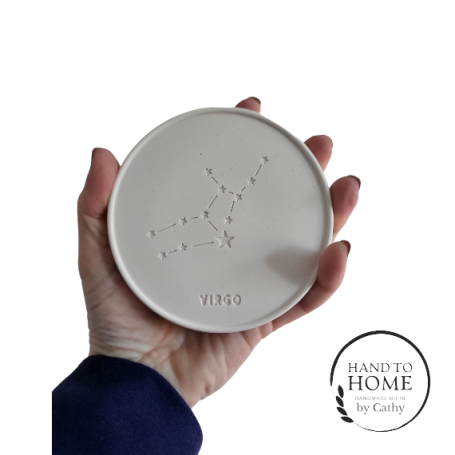 Round White Jesmonite Coaster, White in colour with a star sign and constellation design. A hand is holding it up to the camera.